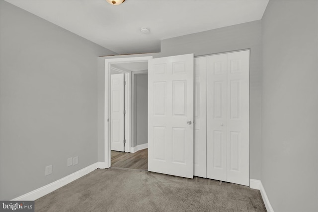 unfurnished bedroom with dark carpet and a closet