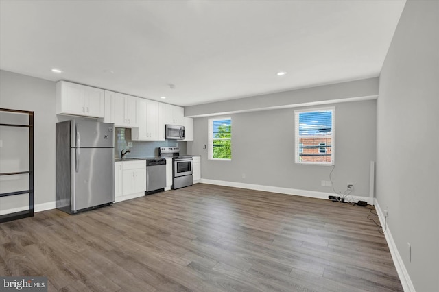 kitchen with white cabinets, decorative backsplash, wood-type flooring, and appliances with stainless steel finishes