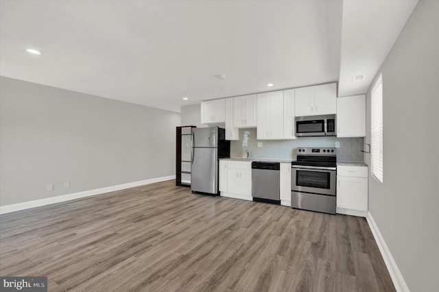 kitchen featuring stainless steel appliances, white cabinetry, plenty of natural light, and light hardwood / wood-style floors