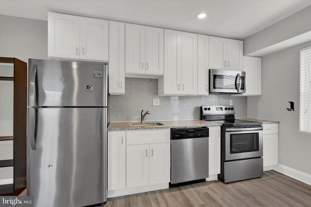 kitchen with hardwood / wood-style floors, sink, white cabinets, and stainless steel appliances