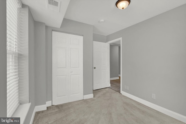 unfurnished bedroom with light carpet and a closet