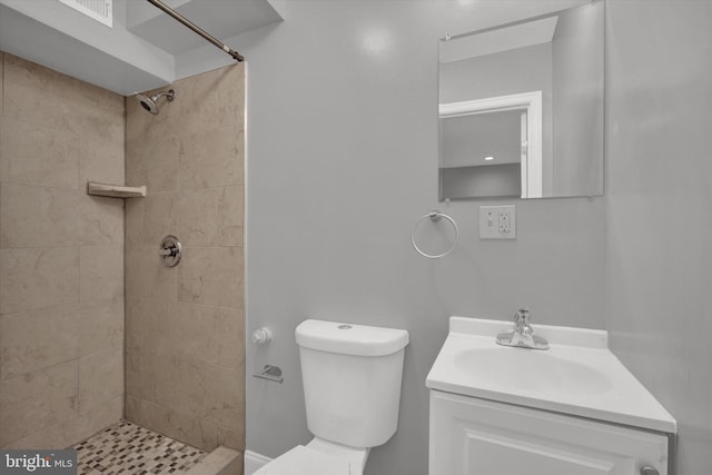 bathroom with a tile shower, vanity, and toilet