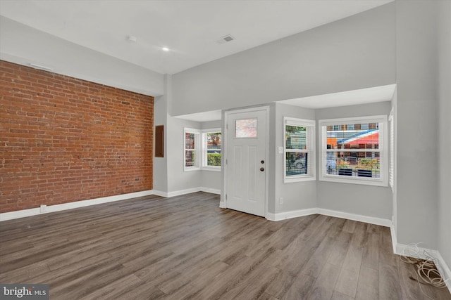 entryway featuring brick wall and wood-type flooring