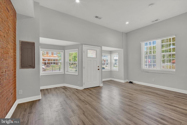 entrance foyer featuring electric panel, light hardwood / wood-style flooring, and brick wall