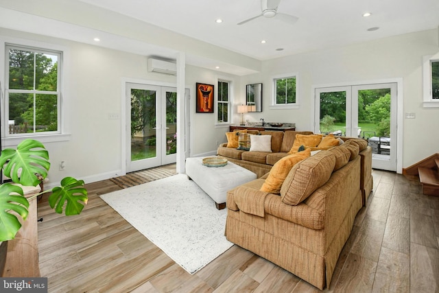 living room with ceiling fan, light hardwood / wood-style flooring, a wall unit AC, and french doors