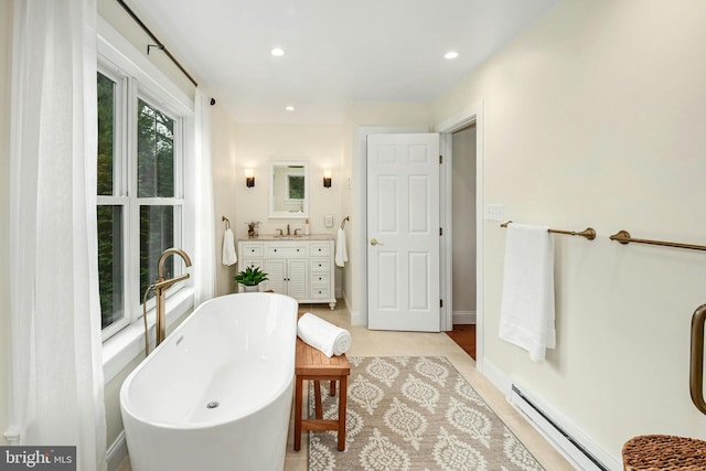 bathroom with vanity, a tub to relax in, and a baseboard radiator