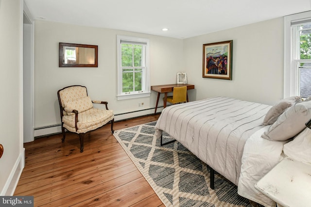 bedroom featuring hardwood / wood-style floors and a baseboard heating unit