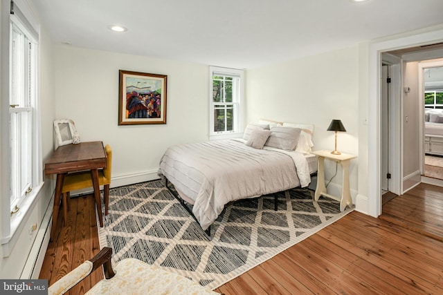 bedroom with baseboard heating and dark hardwood / wood-style flooring