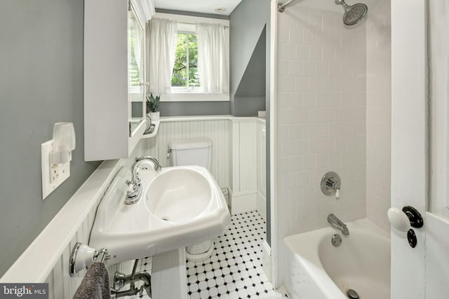 full bathroom featuring tile patterned flooring, toilet, tiled shower / bath, and sink