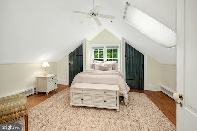 bedroom with ceiling fan, a baseboard radiator, light hardwood / wood-style floors, and vaulted ceiling