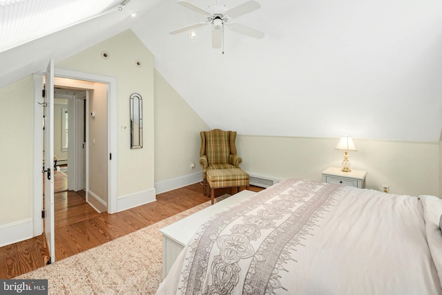 bedroom with baseboard heating, ceiling fan, wood-type flooring, and vaulted ceiling