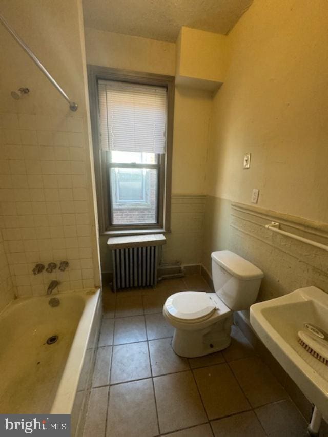 full bathroom with tile patterned floors, sink, toilet, tile walls, and radiator heating unit