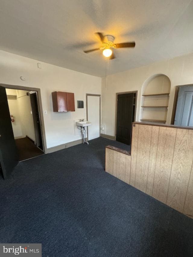 carpeted empty room with ceiling fan, built in features, and sink