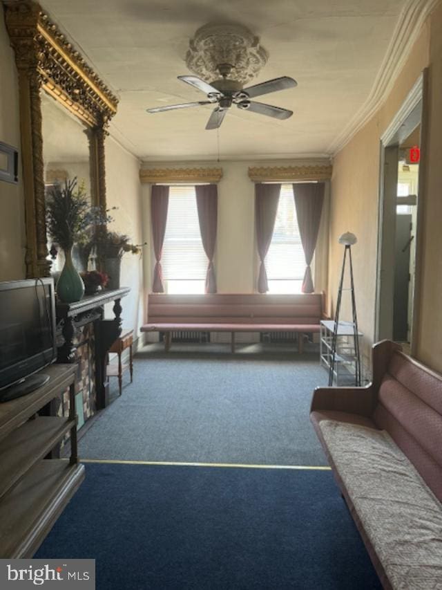 living area featuring ceiling fan, carpet floors, and ornamental molding