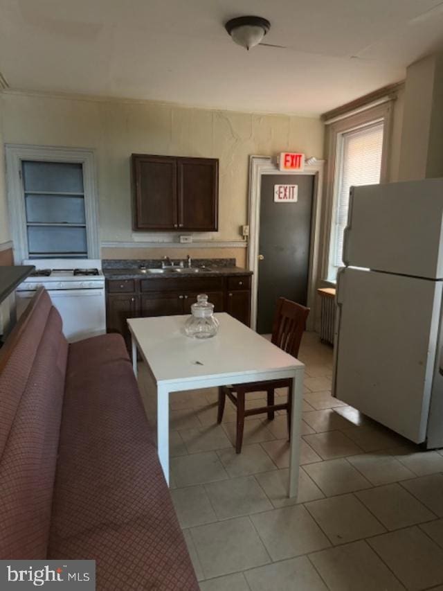 kitchen featuring dark brown cabinets, white refrigerator, light tile patterned floors, and sink