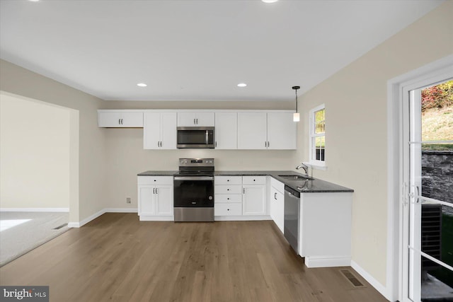 84 Limerick Ln, Selinsgrove, PA 17870 - kitchen with stainless steel appliances, dark countertops, a sink, white cabinets, and wood finished floors