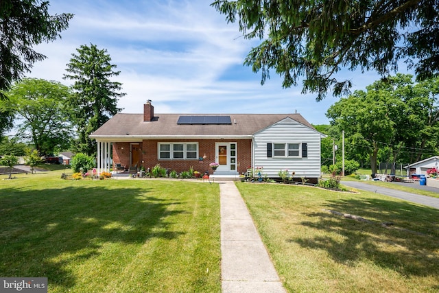 view of front of property with a front yard and solar panels