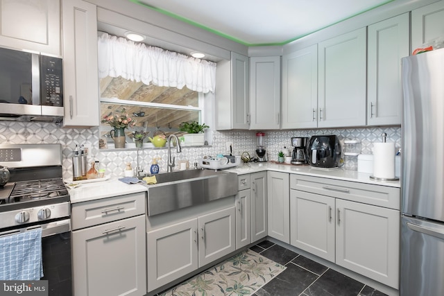 kitchen featuring appliances with stainless steel finishes, backsplash, dark tile patterned floors, and sink