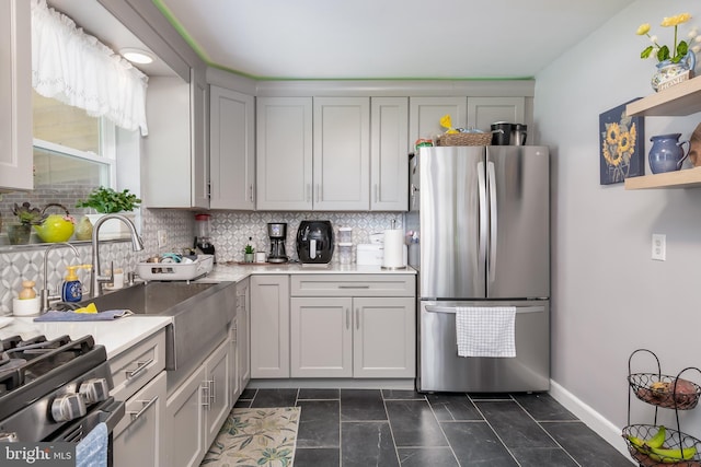 kitchen featuring sink, backsplash, gray cabinets, dark tile patterned flooring, and appliances with stainless steel finishes