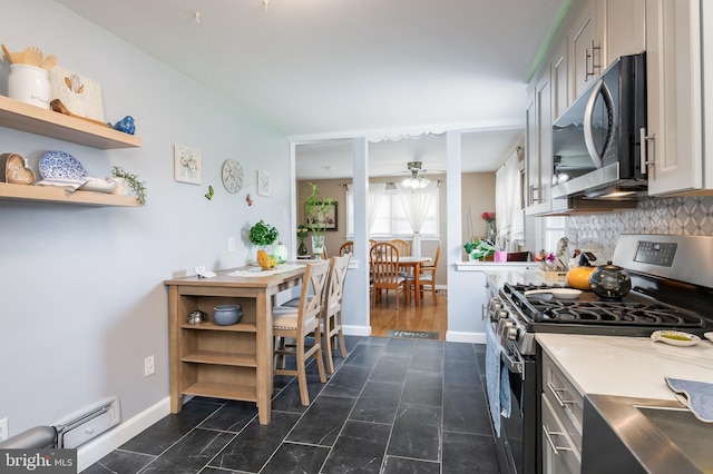 kitchen featuring tasteful backsplash, appliances with stainless steel finishes, a baseboard radiator, and ceiling fan