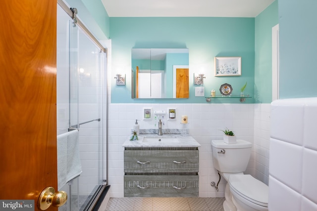 bathroom featuring vanity, tile patterned flooring, toilet, tile walls, and an enclosed shower