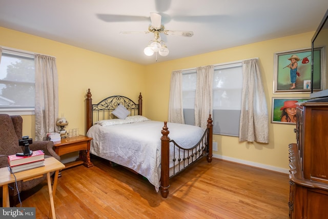 bedroom featuring ceiling fan, light hardwood / wood-style floors, and multiple windows