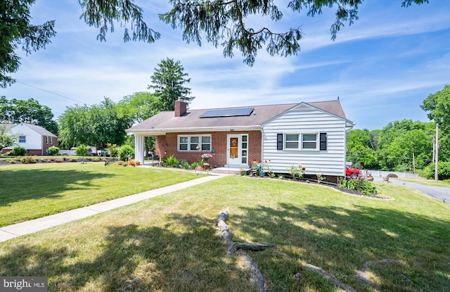 view of front of home featuring solar panels and a front yard