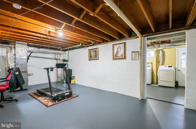 exercise area featuring heating unit and washing machine and clothes dryer