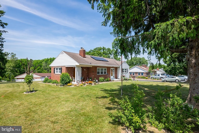 single story home with a front yard and solar panels