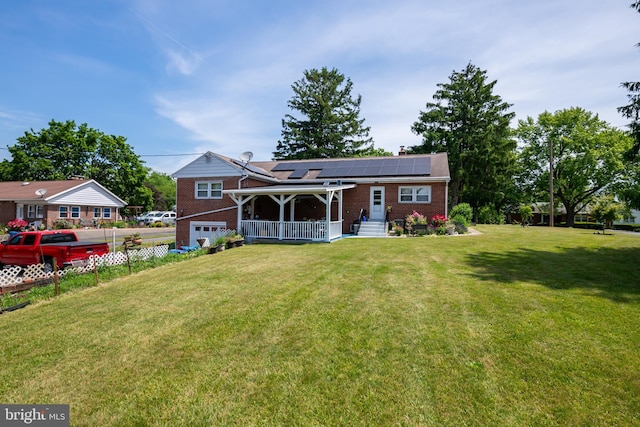 back of property featuring covered porch, solar panels, a garage, and a lawn