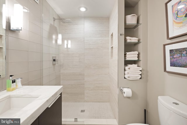 bathroom featuring tiled shower, vanity, and toilet