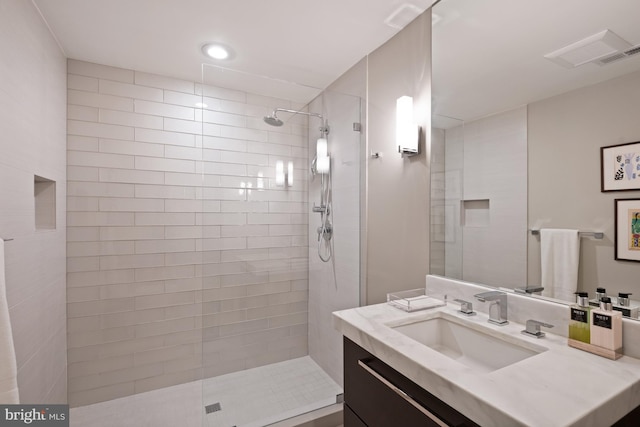 bathroom with tiled shower and vanity