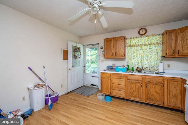 kitchen with ceiling fan, white range oven, sink, and light hardwood / wood-style flooring