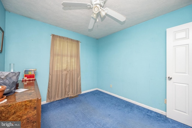 unfurnished bedroom featuring ceiling fan, dark carpet, and a textured ceiling