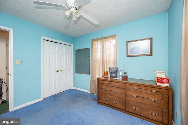 bedroom with dark colored carpet, ceiling fan, a textured ceiling, and a closet