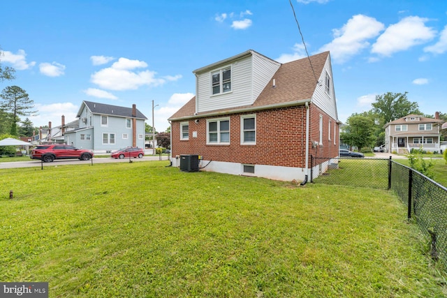 rear view of property with a yard and central AC unit