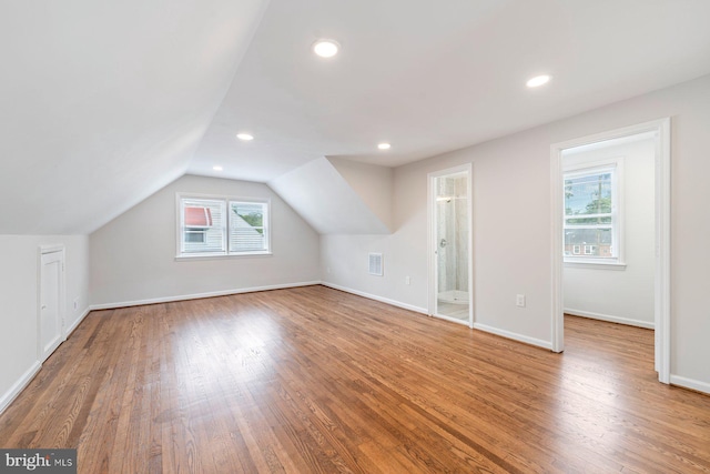 additional living space with wood-type flooring and vaulted ceiling