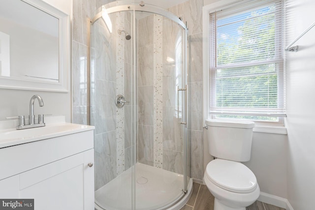 bathroom featuring hardwood / wood-style floors, vanity, toilet, and a shower with door