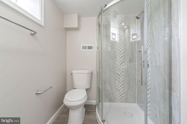 bathroom featuring hardwood / wood-style flooring, toilet, and a shower with shower door