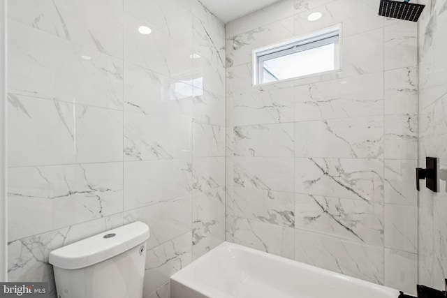 bathroom featuring tiled shower / bath combo, toilet, and tile walls