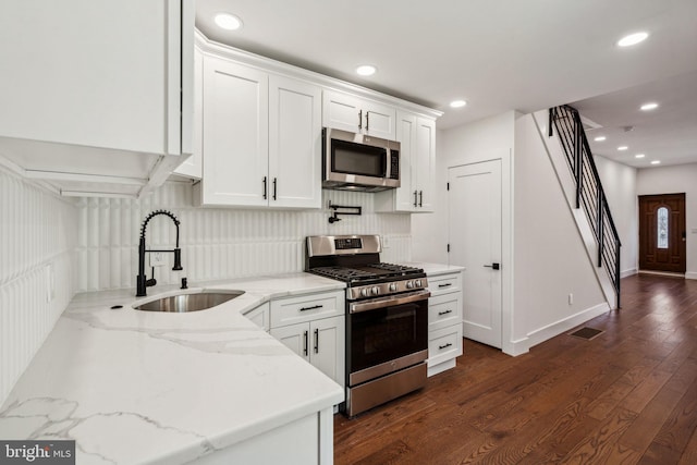 kitchen with white cabinets, dark hardwood / wood-style floors, sink, and appliances with stainless steel finishes