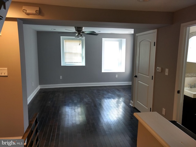 spare room with ceiling fan, sink, and dark wood-type flooring