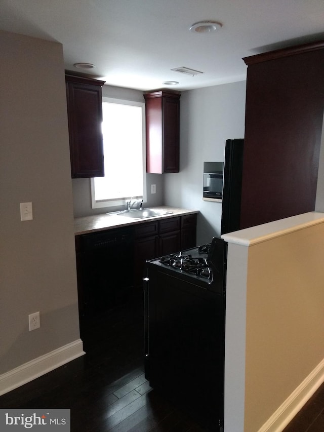 kitchen with dark wood-type flooring, sink, and black appliances