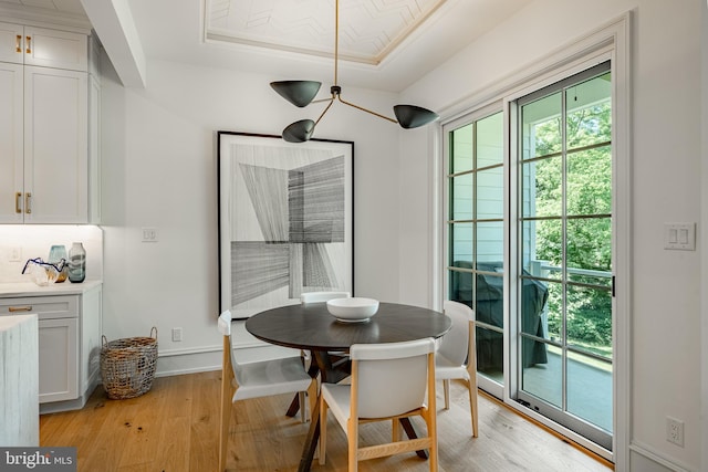 dining space featuring a raised ceiling and light hardwood / wood-style floors