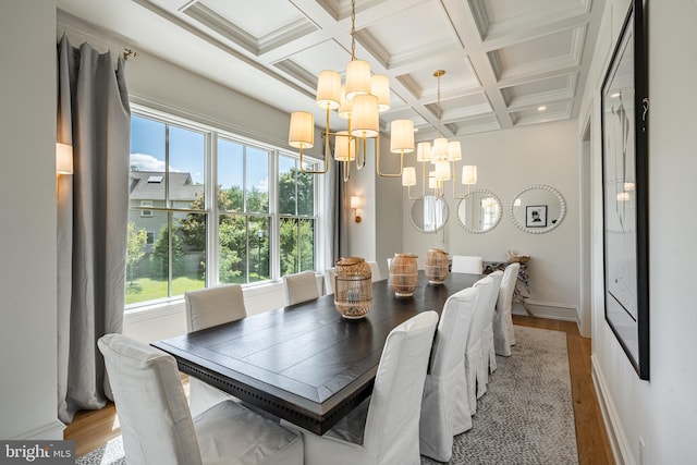 dining area featuring beam ceiling, coffered ceiling, a notable chandelier, light hardwood / wood-style floors, and ornamental molding