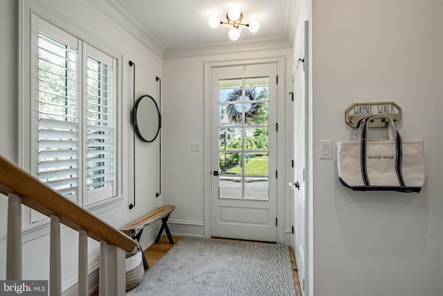 entryway featuring light hardwood / wood-style floors, an inviting chandelier, a healthy amount of sunlight, and ornamental molding