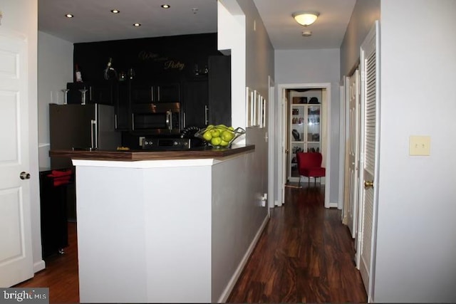 kitchen featuring kitchen peninsula, dark wood-type flooring, and stainless steel appliances