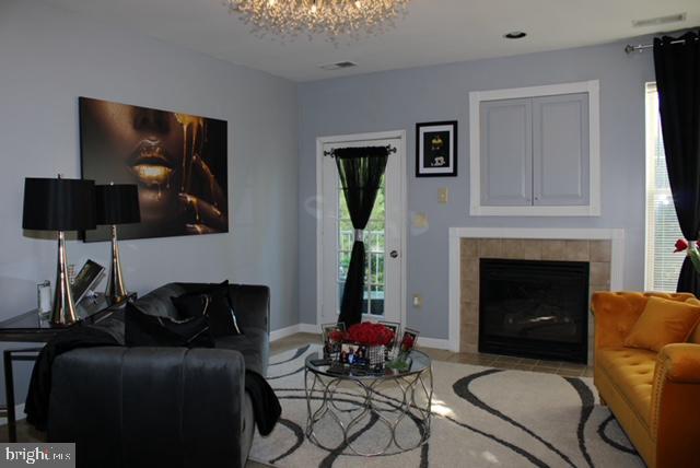 living room featuring an inviting chandelier and a tiled fireplace