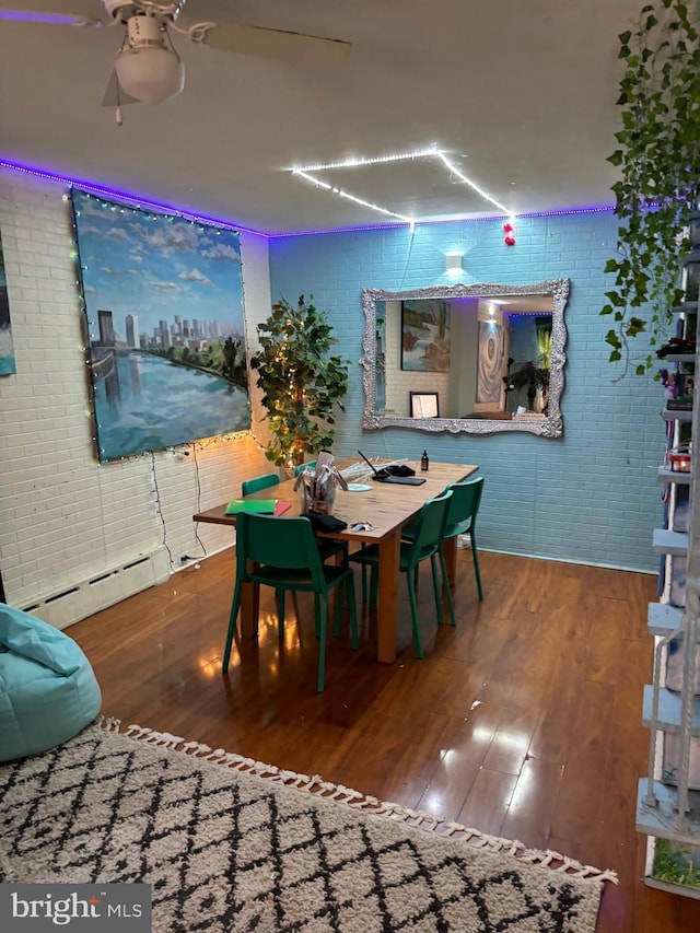 dining room with hardwood / wood-style floors, brick wall, and a baseboard heating unit