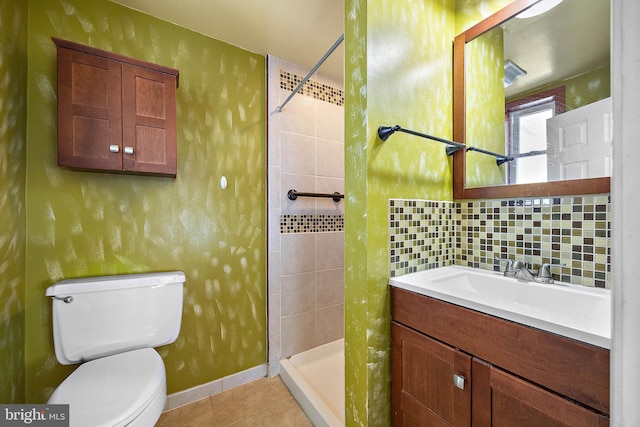 bathroom with tasteful backsplash, tile patterned floors, vanity, tiled shower, and toilet